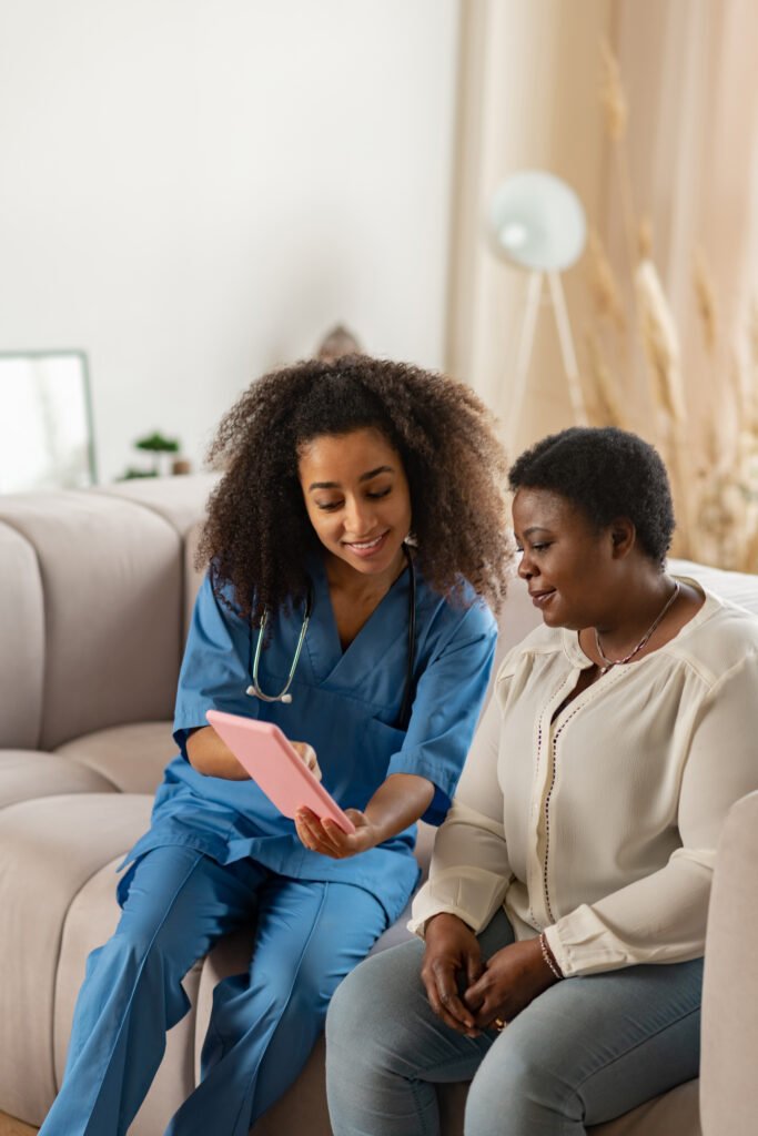 pleasant curly nurse showing online news to elderly lady pleasant curly nurse showing online news to elderly lady