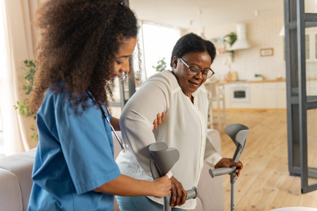 curly young nurse giving crutches to aged woman after leg surgery