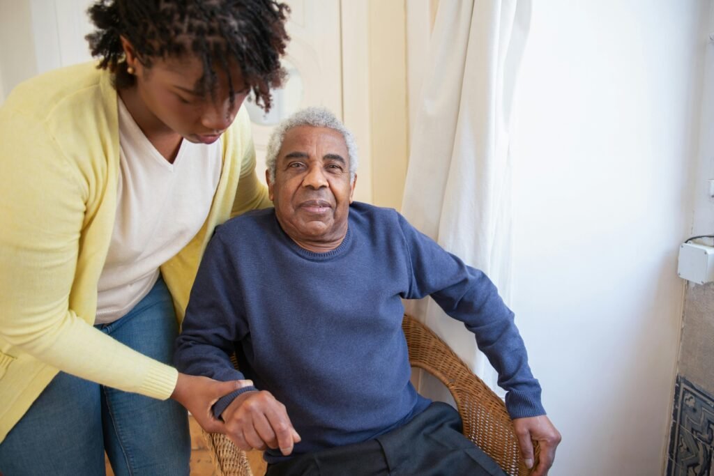 A woman assists an elderly man indoors, focusing on care and support.